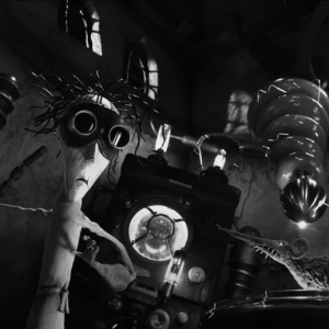 Black and white screenshot of an animated stop-motion scene inside a lab where the main foregrounded character wears goggles.